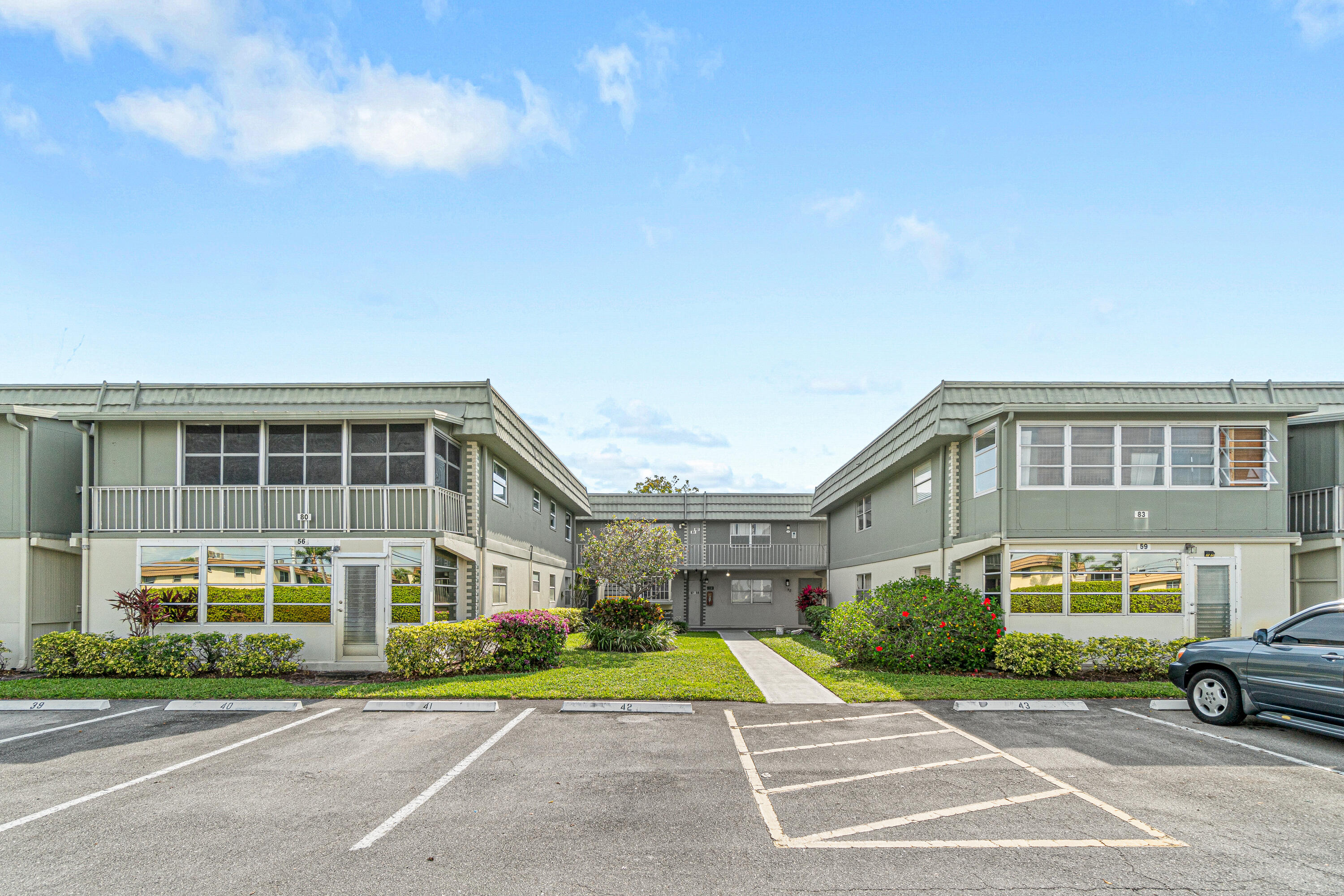80 Flanders B Delray Beach, FL 33484 - Photo 22 of 26 a front view of a building with a garden and trees