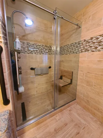 a bathroom with a shower and a chair