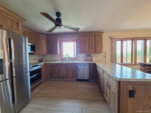 a kitchen with stainless steel appliances granite countertop a refrigerator a sink dishwasher a stove and white countertops with wooden floor