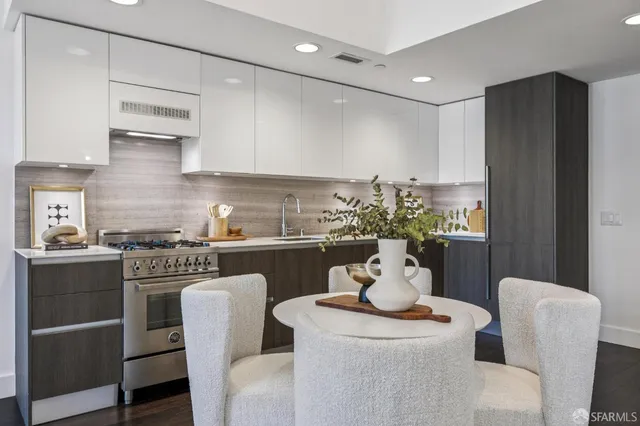 a kitchen with stainless steel appliances granite countertop a dining table chairs and white cabinets