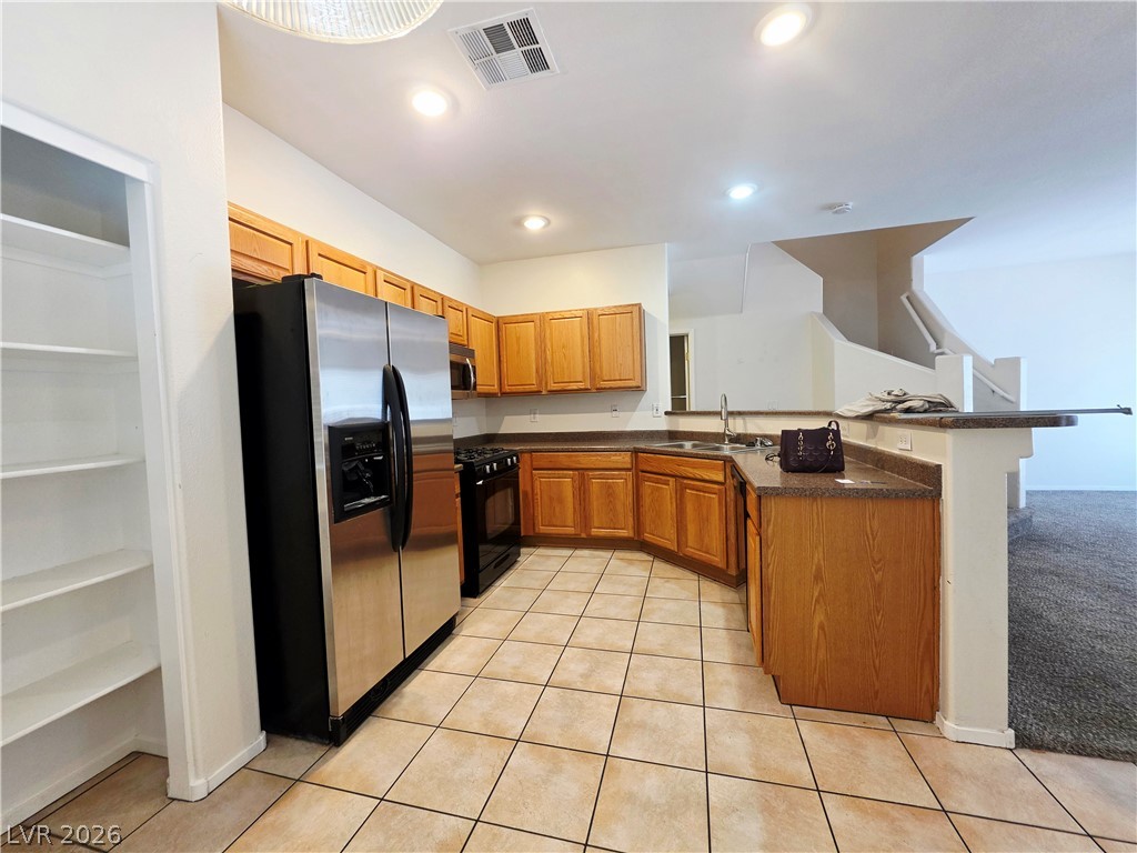 1571 Rusty Ridge Lane Henderson, NV 89002 - Photo 6 of 26 A functional kitchen boasts ample cabinetry, stainless steel appliances, and a convenient breakfast bar.