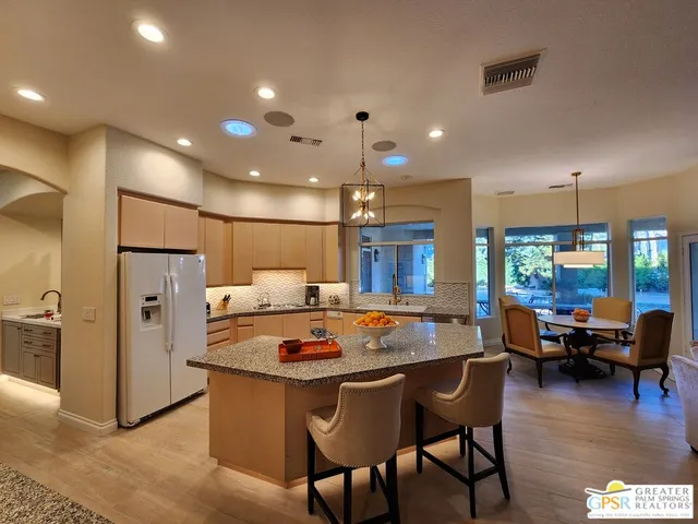 a kitchen with granite countertop a table chairs stove and refrigerator