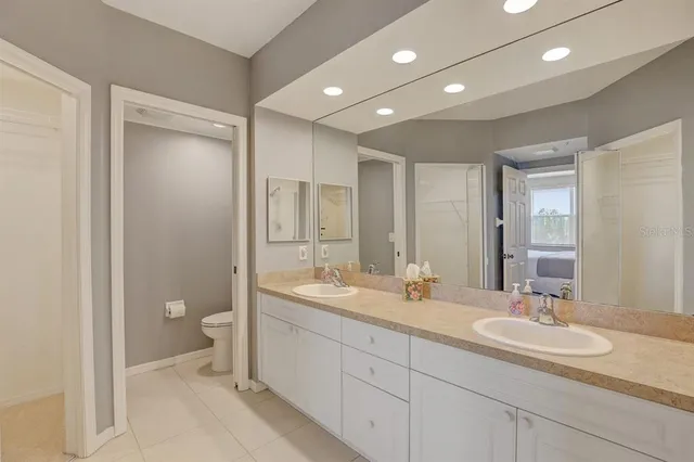 a bathroom with a granite countertop sink a toilet and a large mirror