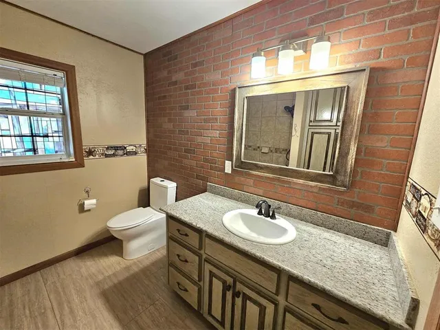a bathroom with a granite countertop sink toilet and mirror