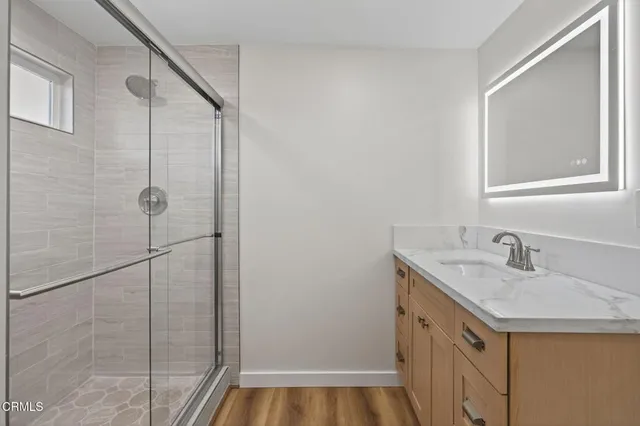 a bathroom with a granite countertop sink a mirror and shower