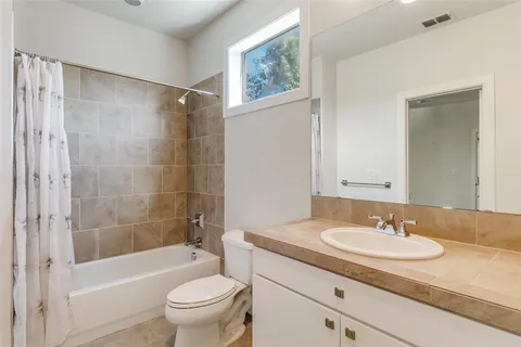 a bathroom with a granite countertop sink a toilet a mirror and a tub