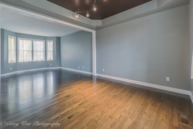 a view of empty room with wooden floor and a window