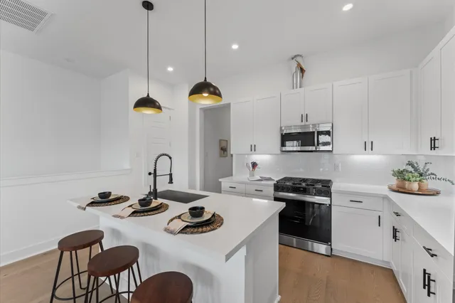 a kitchen with a sink a stove and chairs with wooden floor