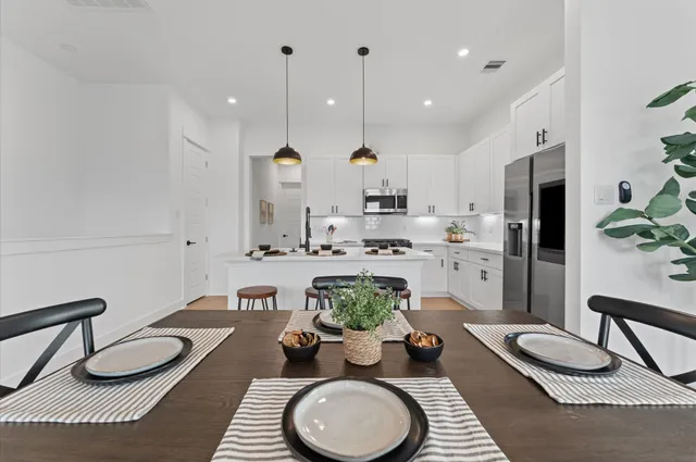 a kitchen with stainless steel appliances a table chairs stove and white cabinets