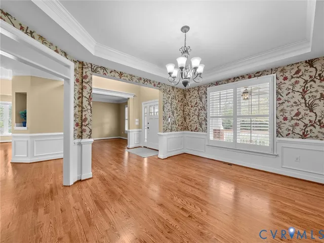 a kitchen with stainless steel appliances granite countertop a stove top oven a sink a dining table and chairs with wooden floor