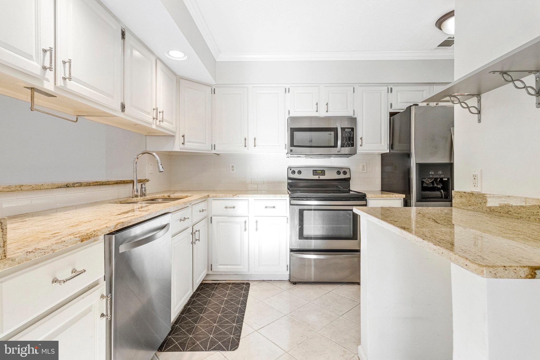 12212 Eagles Nest Court, Unit B Germantown, MD 20874 - Photo 32 of 36 a kitchen with granite countertop a refrigerator and a stove top oven