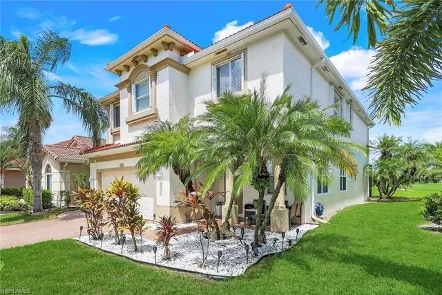 a front view of a house with a garden and trees