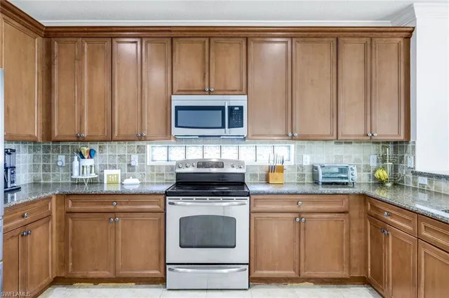 a kitchen with stainless steel appliances granite countertop a stove a microwave a sink and cabinets