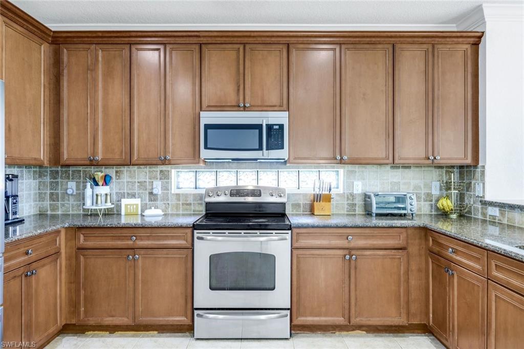 1570 Double Eagle Trail Naples, FL 34120 - Photo 12 of 50 a kitchen with stainless steel appliances granite countertop a stove a microwave a sink and cabinets