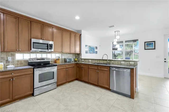 a kitchen with stainless steel appliances granite countertop a stove top oven a sink dishwasher and a refrigerator