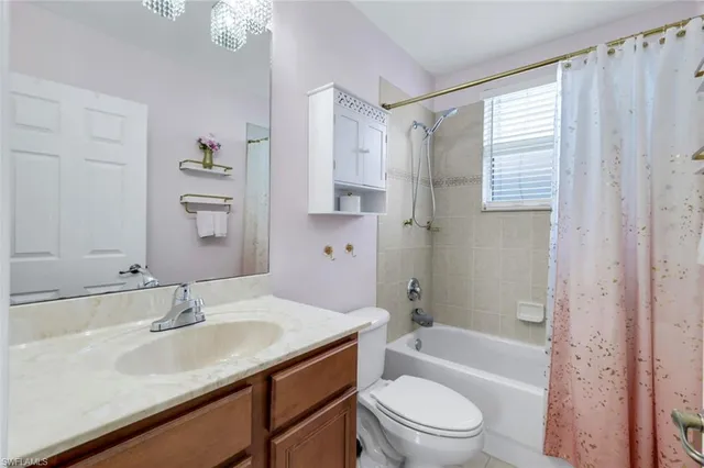 a bathroom with a granite countertop bathtub shower sink vanity mirror and toilet