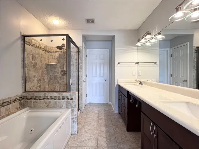 a spacious bathroom with a granite countertop tub sink shower and mirror