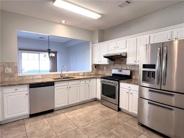 a kitchen with granite countertop stainless steel appliances and white cabinets