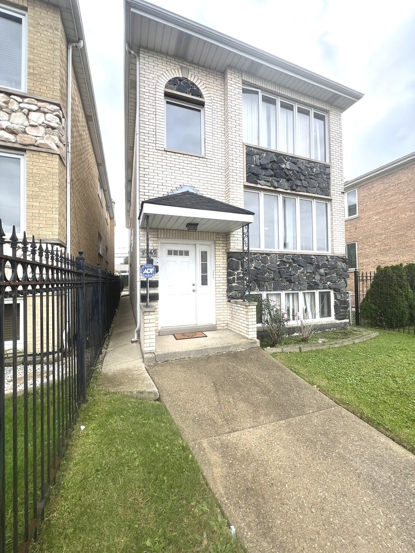 7445 West Belmont Avenue, Unit 1 Chicago, IL 60634 - Photo 3 of 20 a front view of a house with a yard and garage