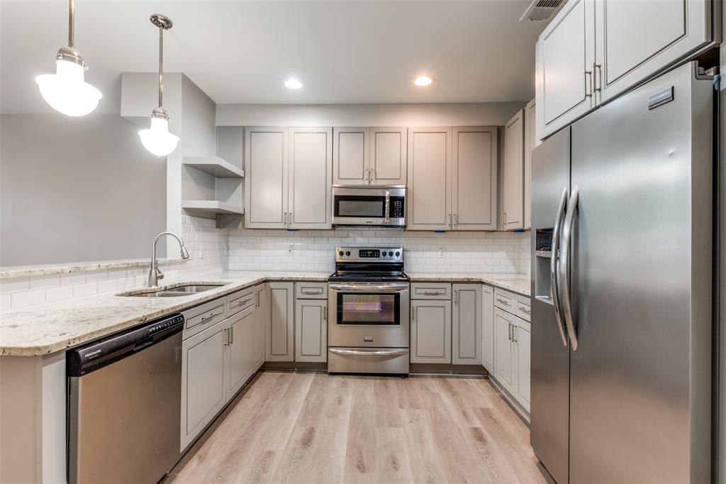 3912 Rawlins Street, Unit 2 Dallas, TX 75219 - Photo 11 of 25 a kitchen with kitchen island granite countertop stainless steel appliances and a sink
