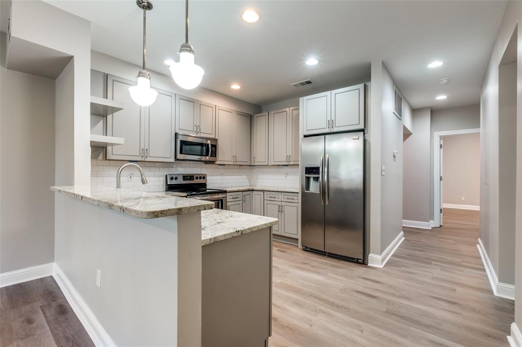3912 Rawlins Street, Unit 2 Dallas, TX 75219 - Photo 10 of 25 a kitchen with stainless steel appliances granite countertop a refrigerator a stove a sink and a microwave