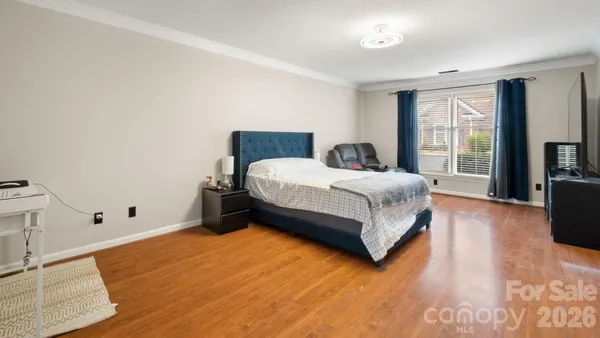 a spacious bedroom with a bed and wooden floor