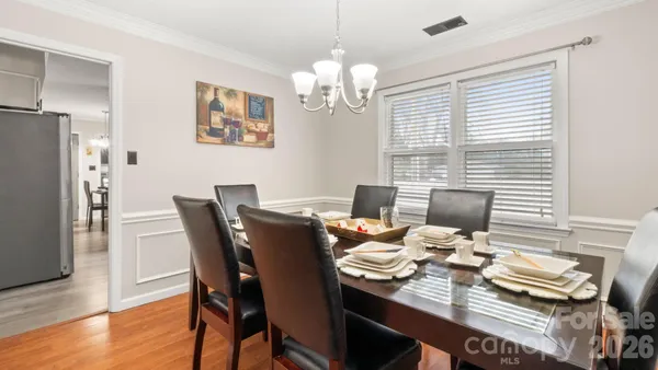 a view of a dining room with furniture a chandelier and wooden floor