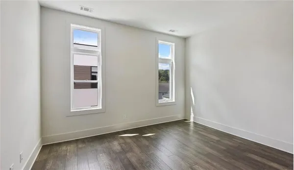 an empty room with wooden floor and windows