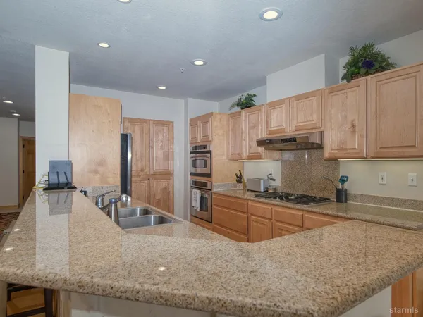 a kitchen with stainless steel appliances granite countertop a sink refrigerator and cabinets