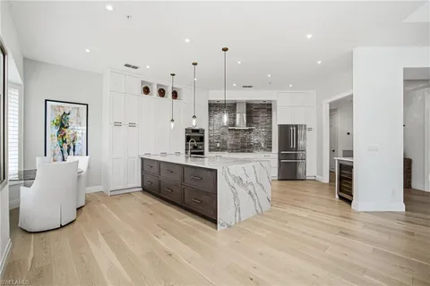a large kitchen with stainless steel appliances kitchen island granite countertop a refrigerator and a sink
