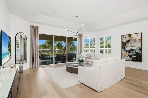 a living room with furniture large window and wooden floor