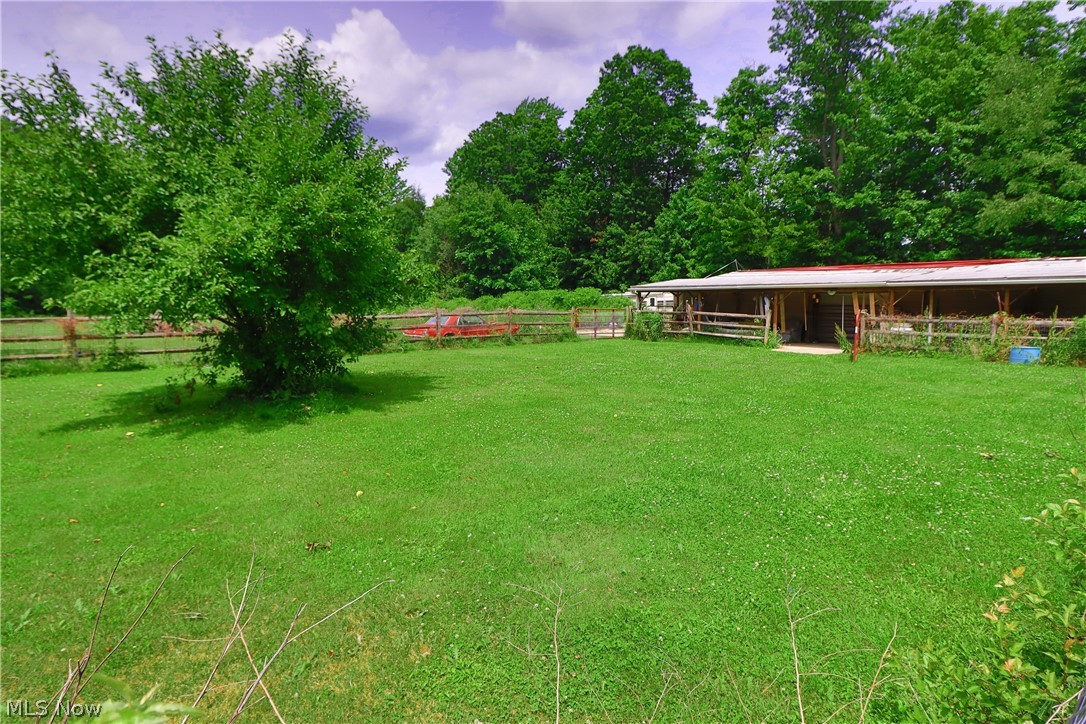 7250 Brakeman Road Painesville, OH 44077 - Photo 8 of 17 Expansive green lawn with mature trees and a long covered outbuilding featuring a red roof