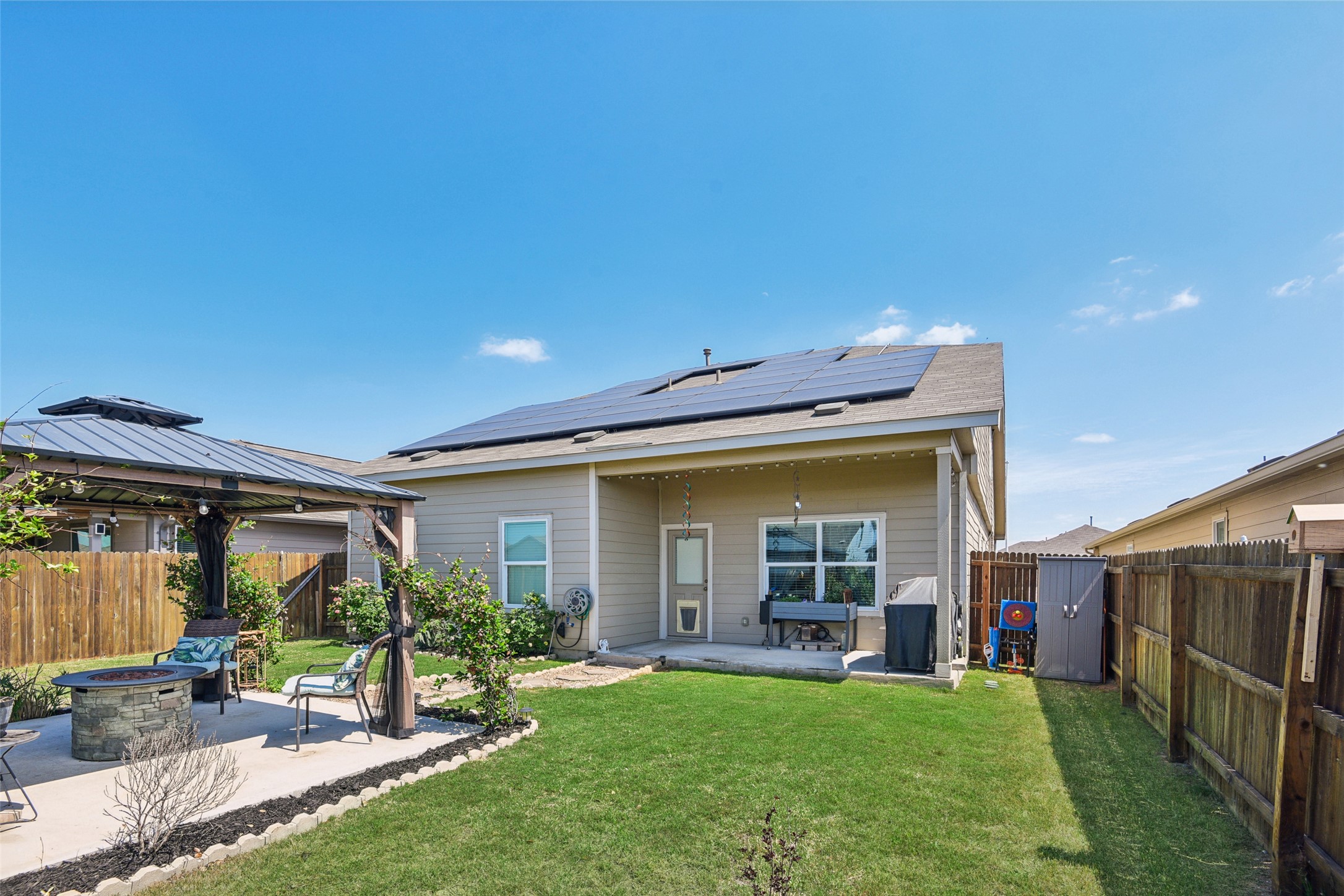 9058 Bowie Ridge Seguin, TX 78155 - Photo 32 of 40 Rear view of house featuring a fire pit, a patio area, roof mounted solar panels, a gazebo, and a fenced backyard