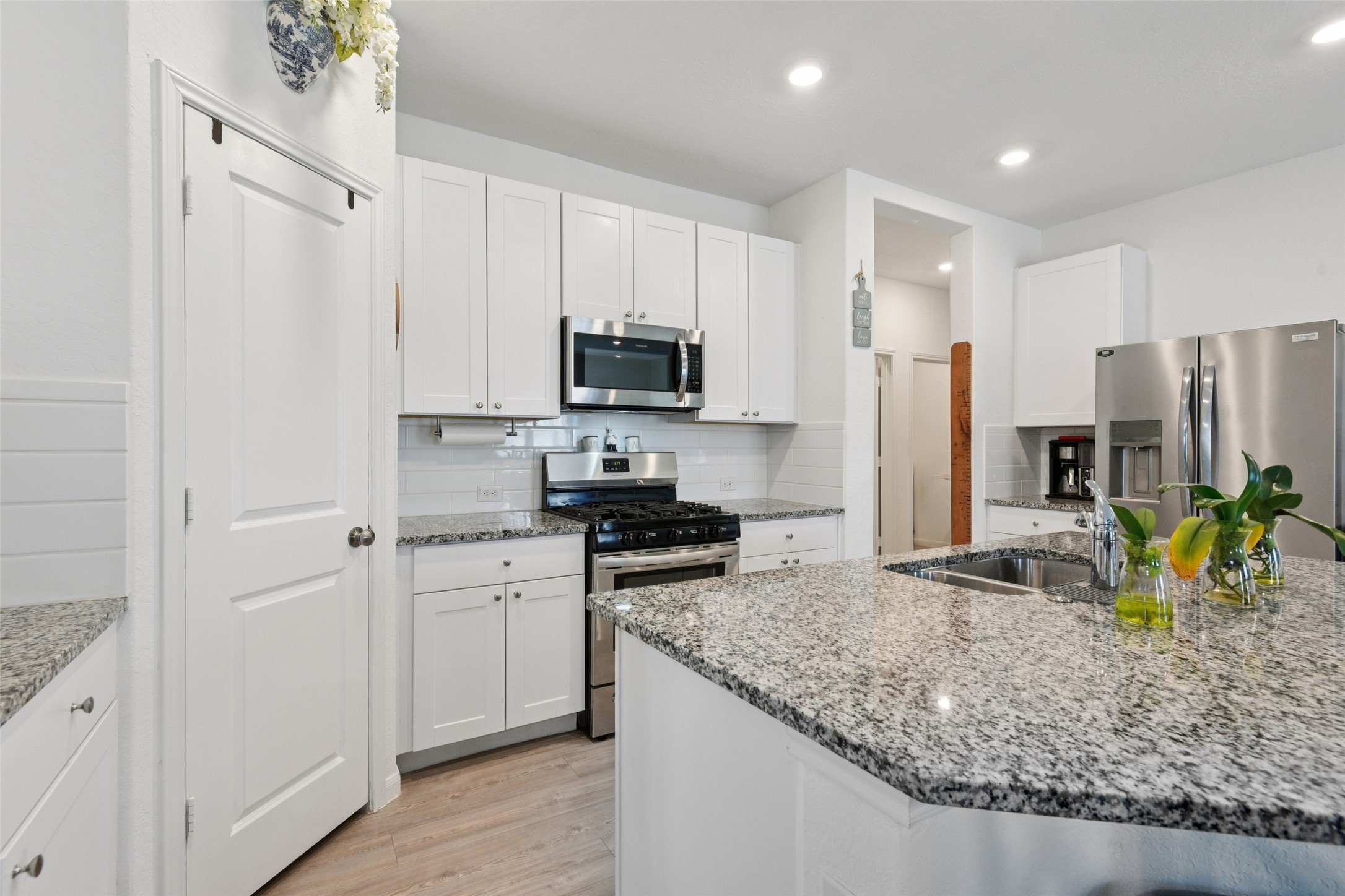 9058 Bowie Ridge Seguin, TX 78155 - Photo 5 of 40 Kitchen featuring stainless steel appliances, decorative backsplash, light wood-type flooring, white cabinetry, and recessed lighting