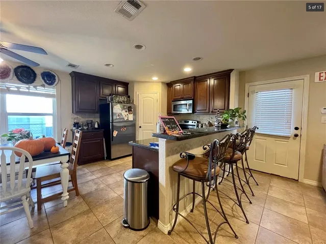 a kitchen with stainless steel appliances kitchen island granite countertop a refrigerator and a stove top oven