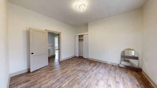 an empty room with wooden floor and mirror