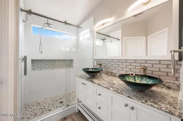 a bathroom with a granite countertop sink a mirror and shower
