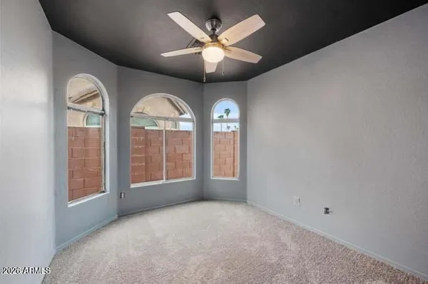 an empty room with chandelier fan and windows