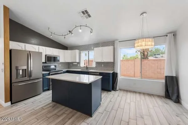 a kitchen with stainless steel appliances granite countertop a refrigerator a sink dishwasher a stove and white countertops with wooden floor