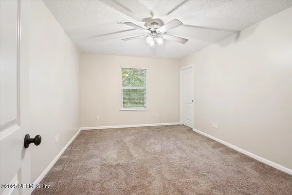 an empty room with windows and fan