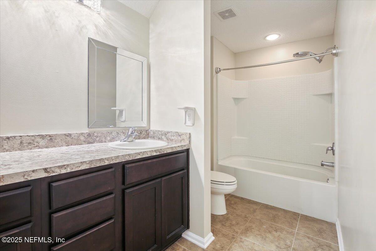4182 Quiet Crk Loop Middleburg, FL 32068 - Photo 16 of 30 a bathroom with a granite countertop sink a toilet and shower
