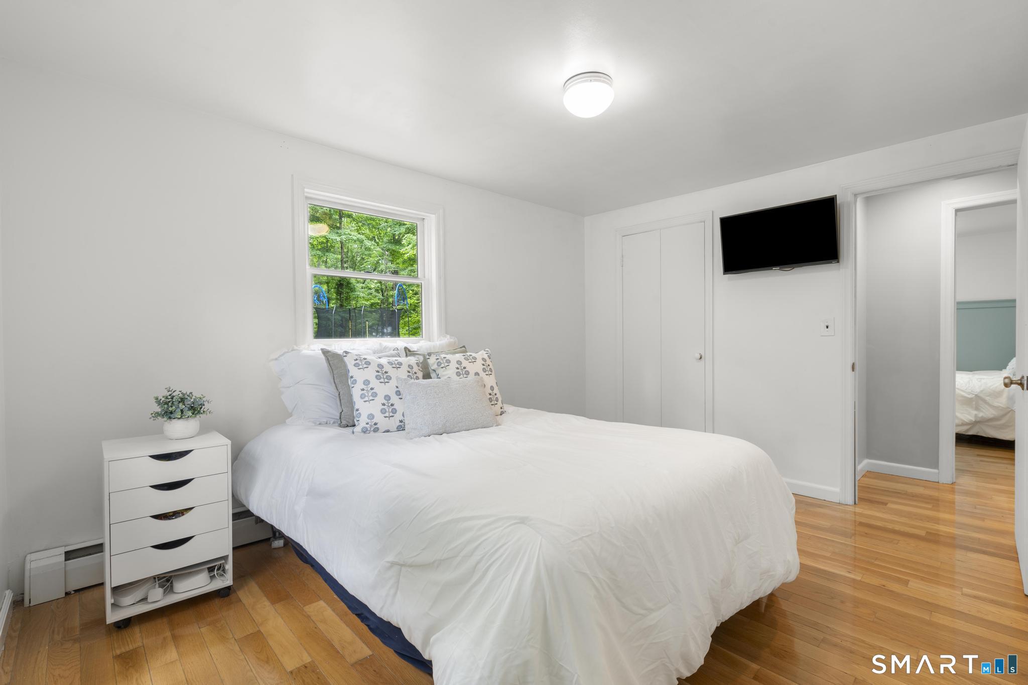 200 Old Huckleberry Road Wilton, CT 06897 - Photo 12 of 24 a bedroom with a bed and a flat tv screen