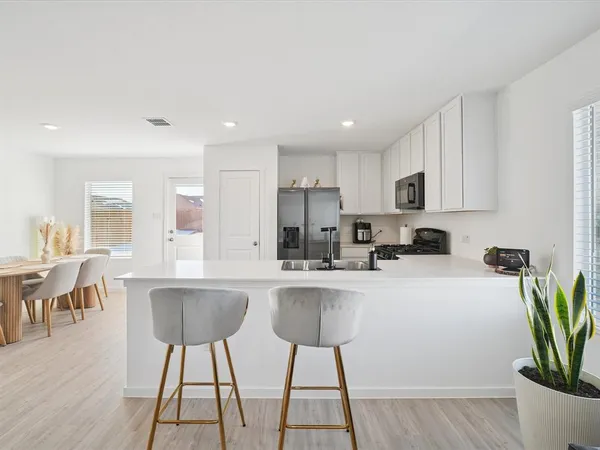 a kitchen with stainless steel appliances a dining table chairs microwave and sink