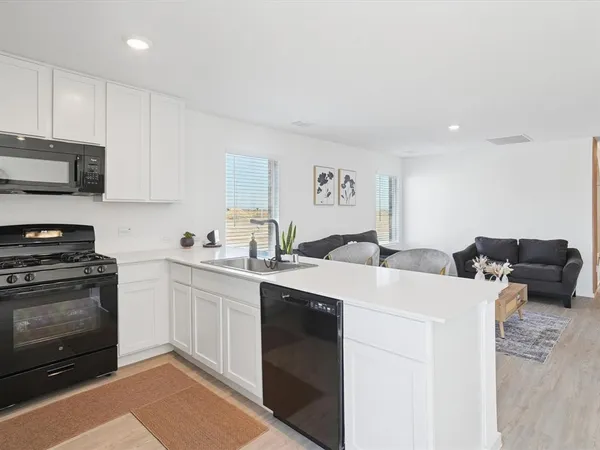 a kitchen with stainless steel appliances a stove a sink a microwave a refrigerator and cabinets