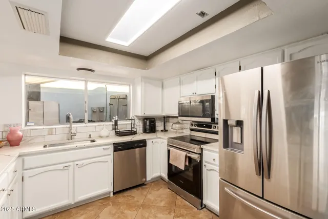 a kitchen with white cabinets and stainless steel appliances