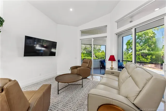 a living room with furniture a flat screen tv and a floor to ceiling window