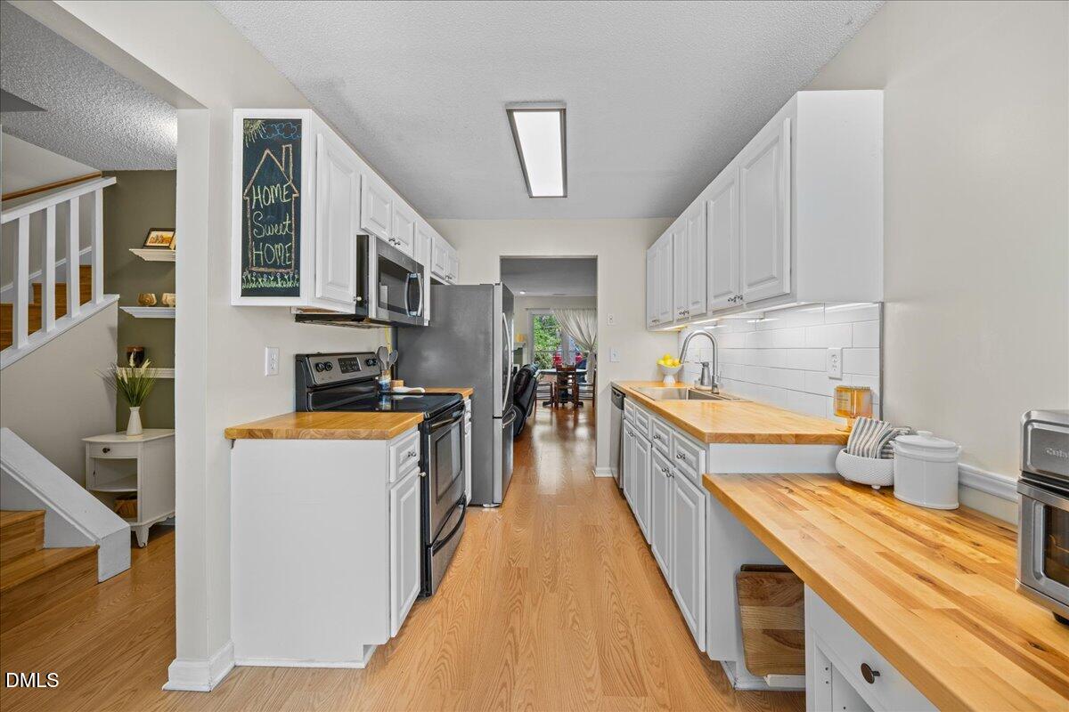 501 Darby Glen Lane Durham, NC 27713 - Photo 6 of 25 a kitchen with stainless steel appliances granite countertop lots of counter top space and wooden floors
