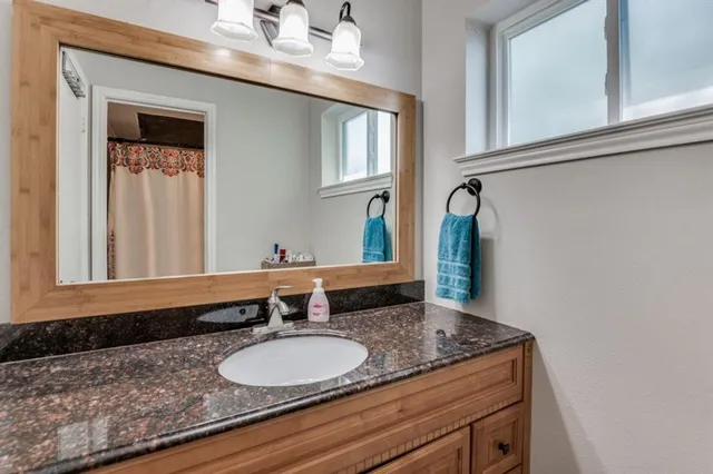 a bathroom with a granite countertop sink and a mirror
