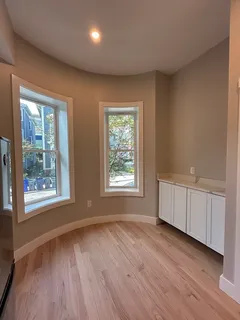 a view of an empty room with a window and wooden floor