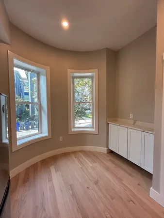 a view of an empty room with a window and wooden floor